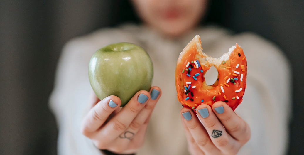 a person holding fruit and doughnut